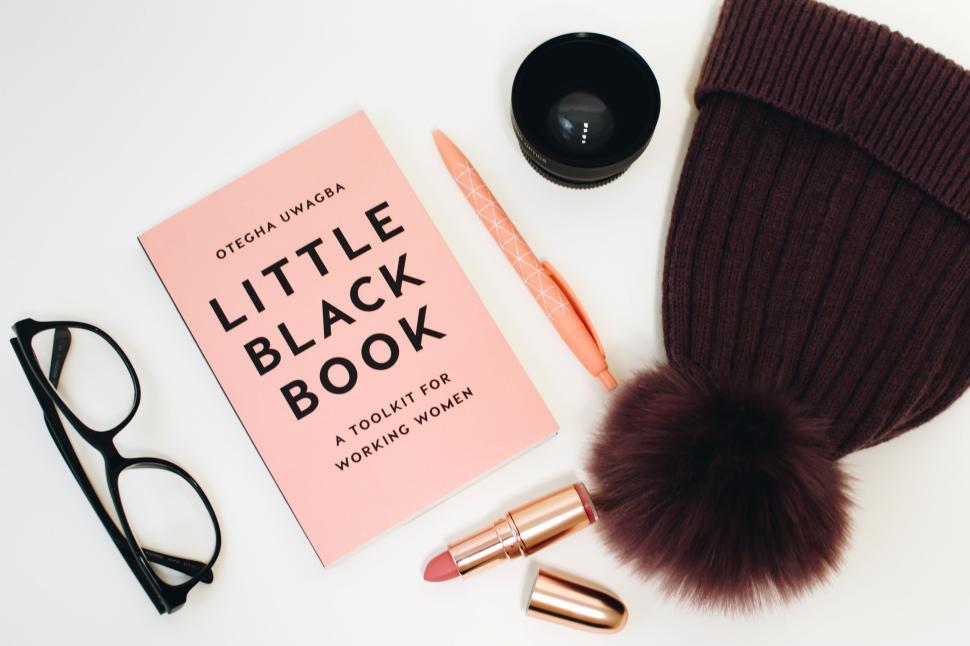 Free Image of Work essentials including a book, glasses, pen, lipstick and hat 