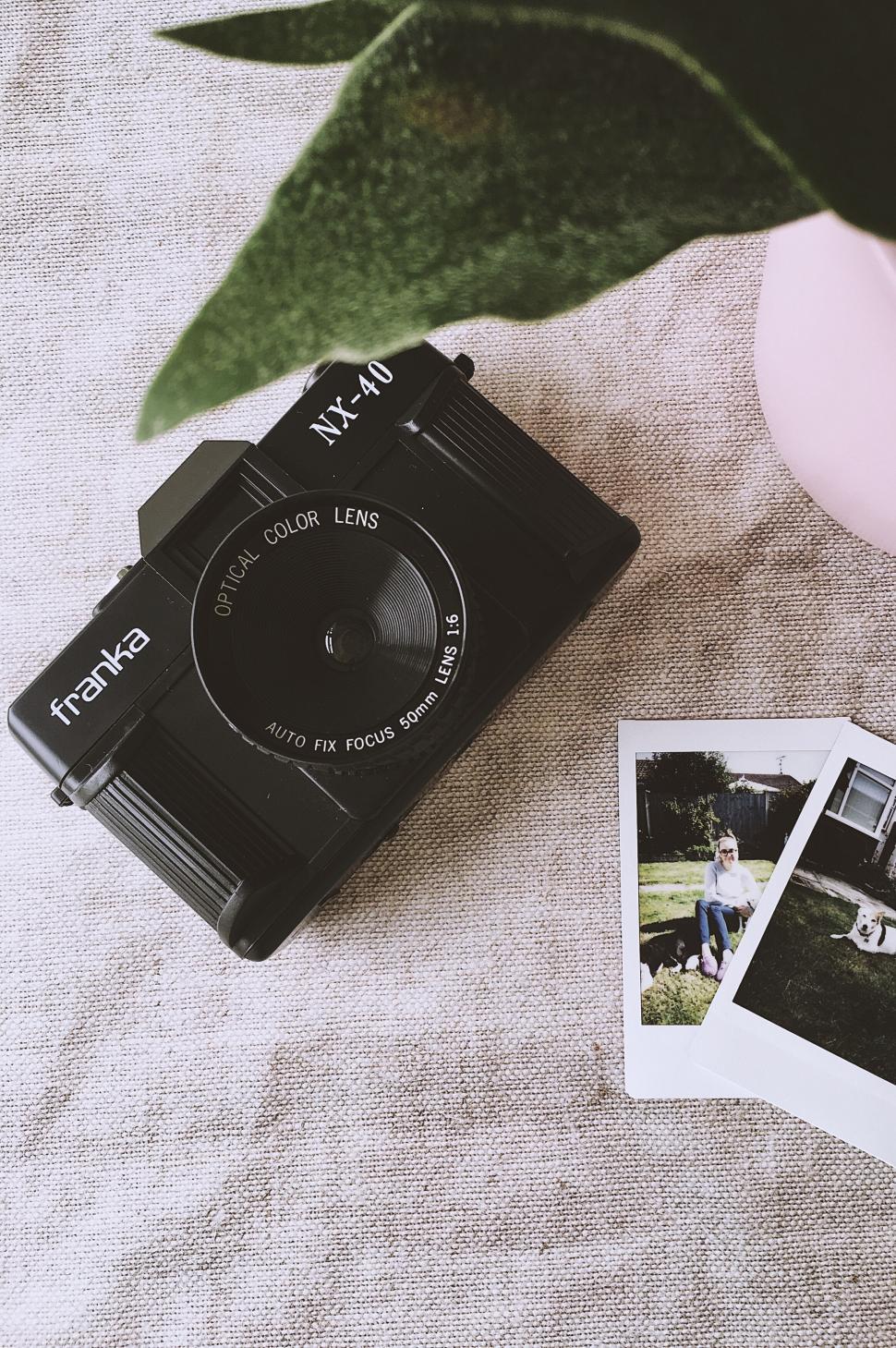 Free Image of Vintage camera and instant photographs on a fabric surface 