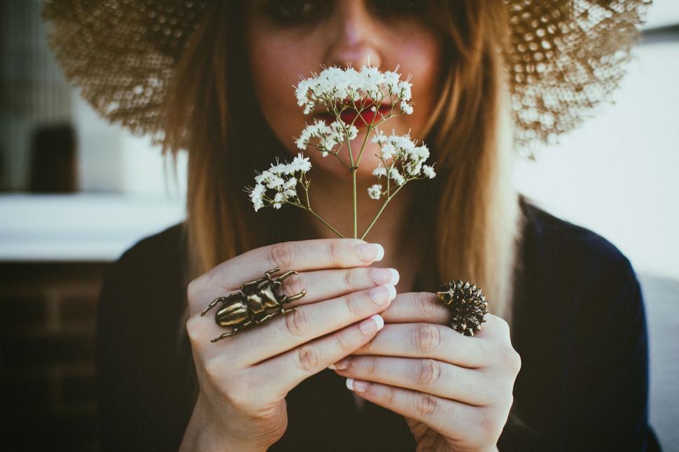 Free Image of Closeup of hands holding flowers wearing artistic insect rings 