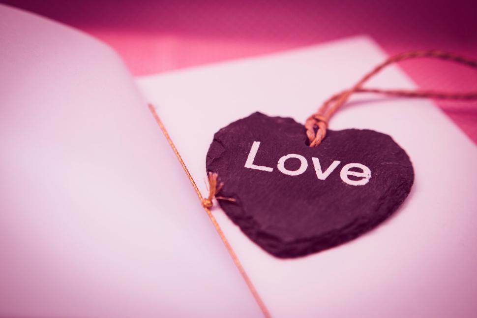 Free Image of Heart-shaped tag with love written on it tied to a pink ribbon 