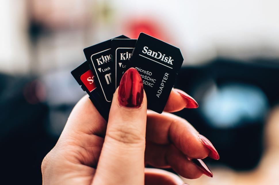 Free Image of Hand holding various SD cards from different brands on blurred background. 