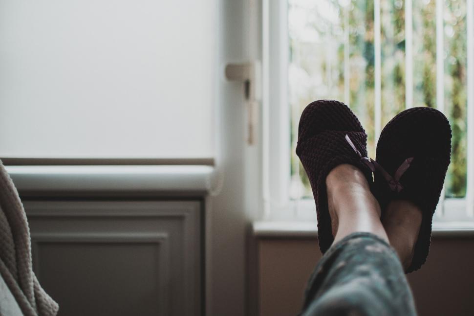 Free Image of Person relaxing with feet up in cozy slippers by a window view 