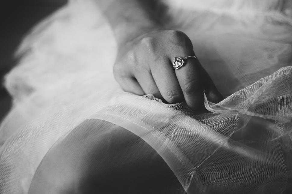 Free Image of Hand with heart-shaped ring on a delicate, sheer white fabric 