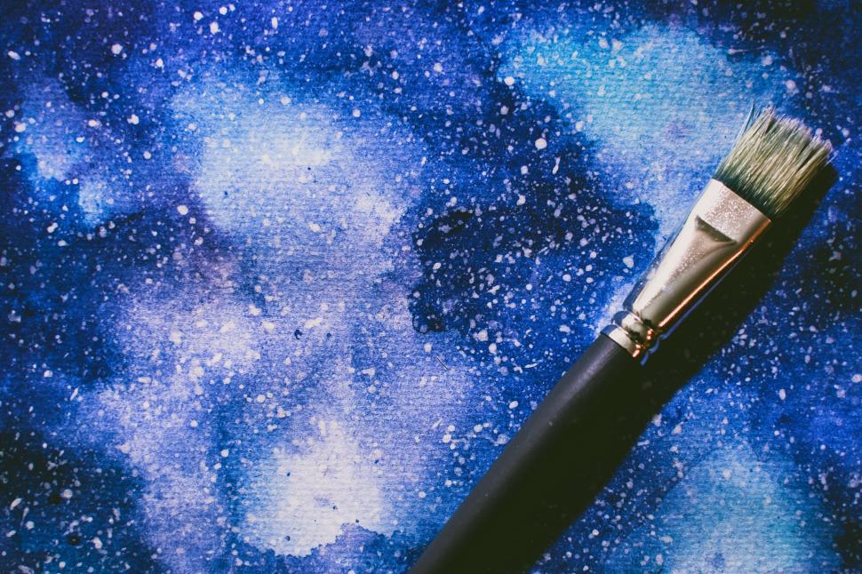 Free Image of Paintbrush with cosmic-inspired artwork in the background 