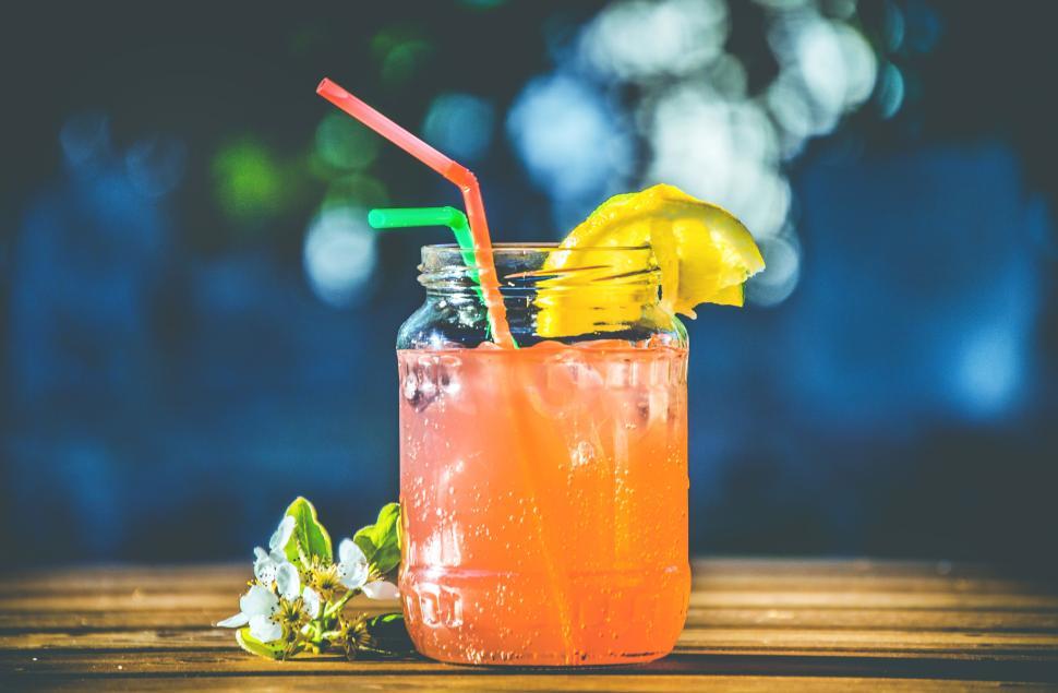 Free Image of Refreshing orange drink with straws and lemon slice in mason jar 