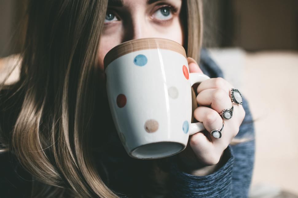 Free Image of Woman with rings holding a white polka dot mug with coffee indoors 