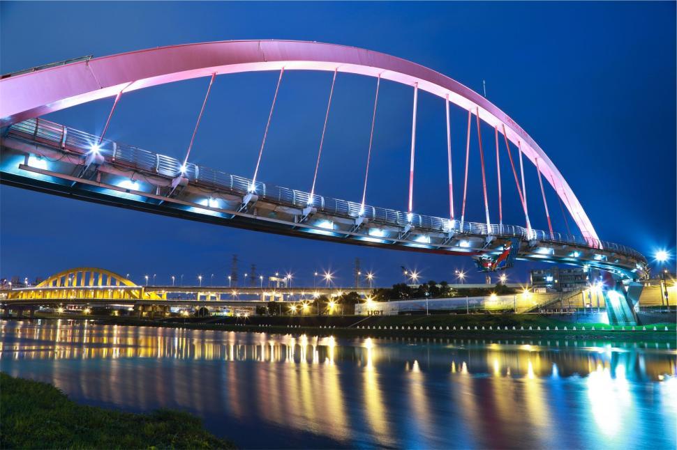Free Image of Illuminated modern bridge with colorful lights reflecting in the water. 