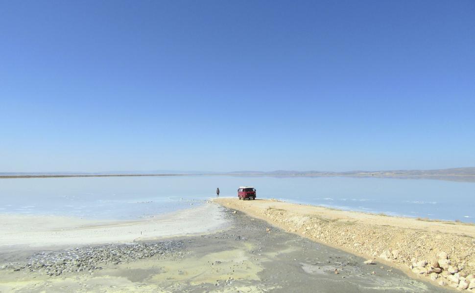 Free Image of Red vehicle parked on a vast salty flatland under a clear blue sky 