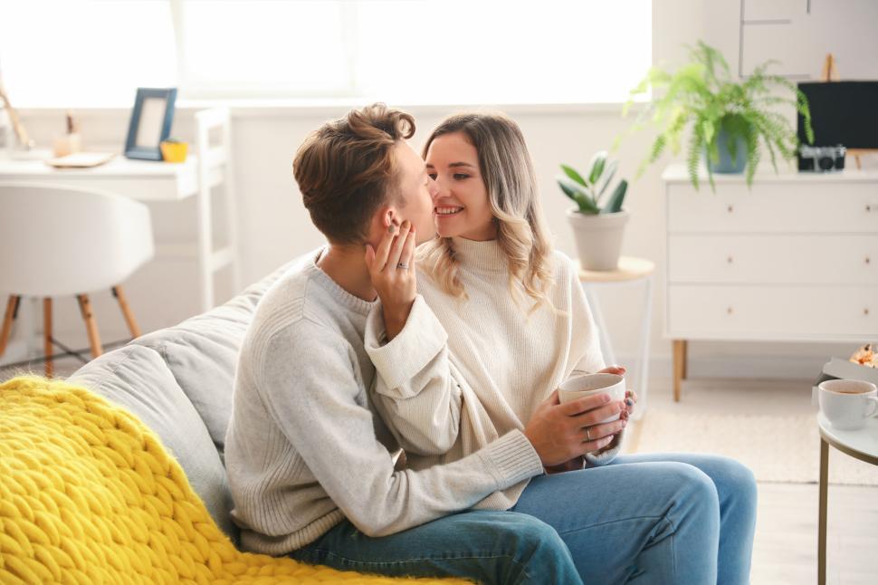 Free Image of Couple sharing a moment on the couch with coffee and smiles 