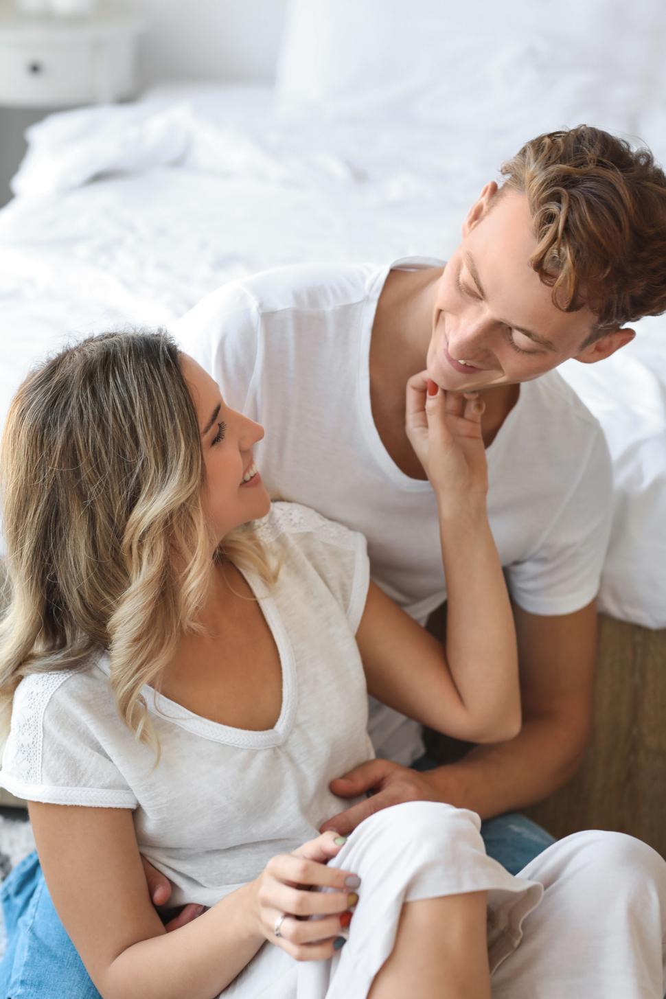 Free Image of Couple sitting on floor in bedroom with woman caressing man s chin 
