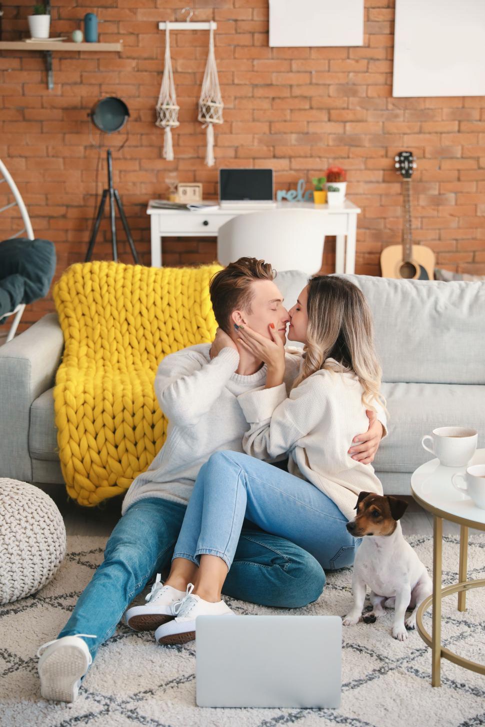 Free Image of Couple sitting on floor, snuggling with dog in cozy living room 
