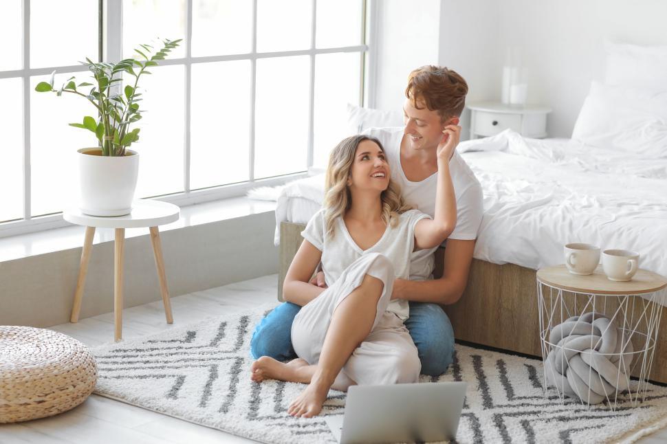 Free Image of Couple sitting on floor in front of bed sharing a loving moment 