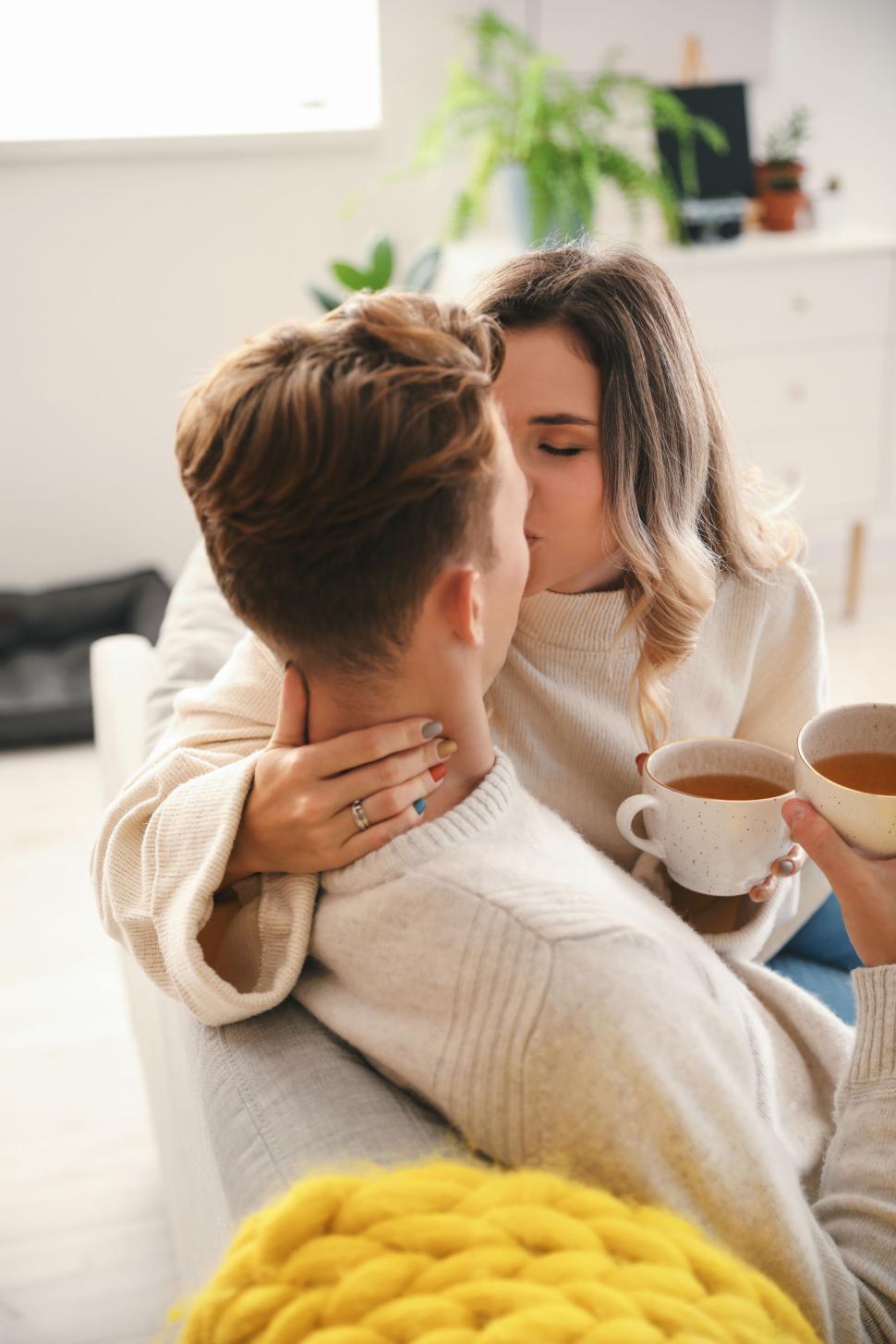 Free Image of Couple sharing a moment with coffee on a cozy couch together. 
