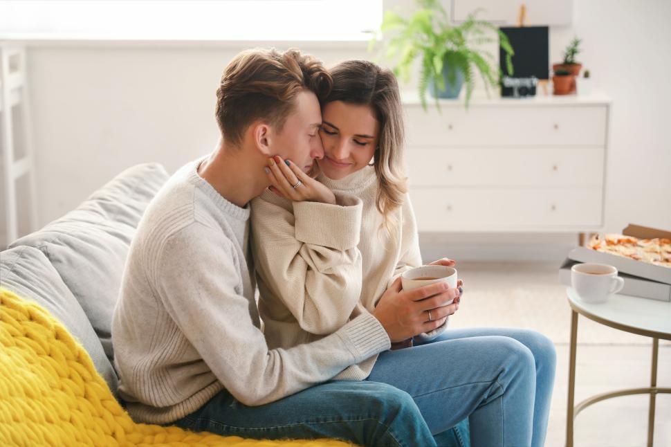 Free Image of Couple cuddling on couch, sharing tender moment, warm atmosphere. 
