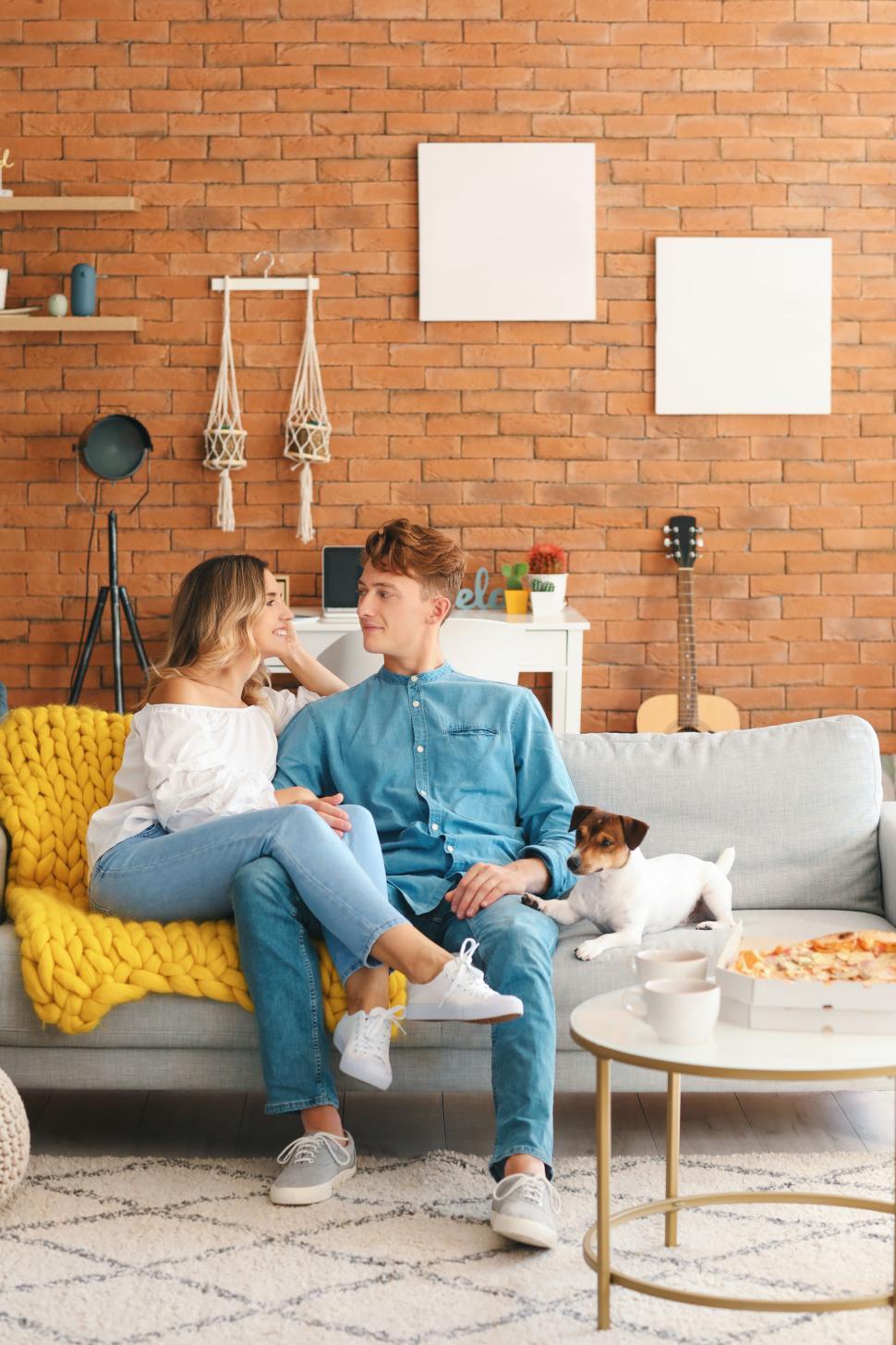 Free Image of Couple on couch with dog, cozy home setting, casual clothes. 