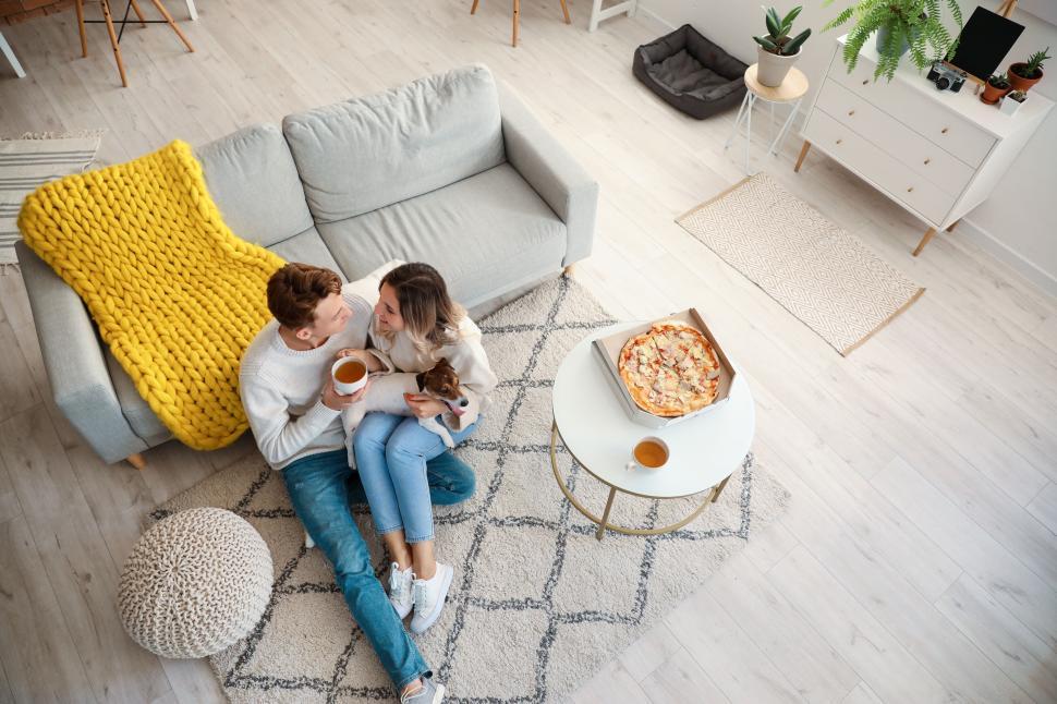 Free Image of Couple enjoying a cozy pizza night on the couch with a blanket. 