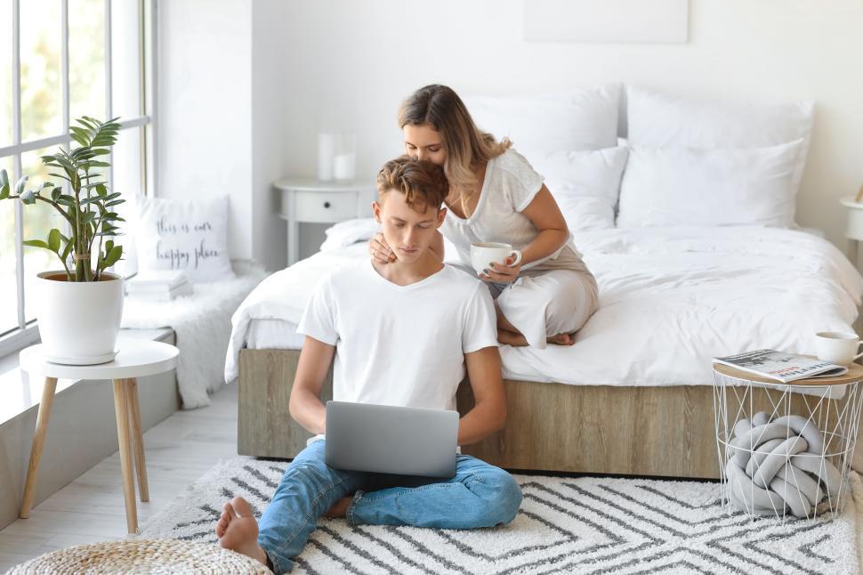 Free Image of Couple bonding over a laptop in a cozy white bedroom setting 