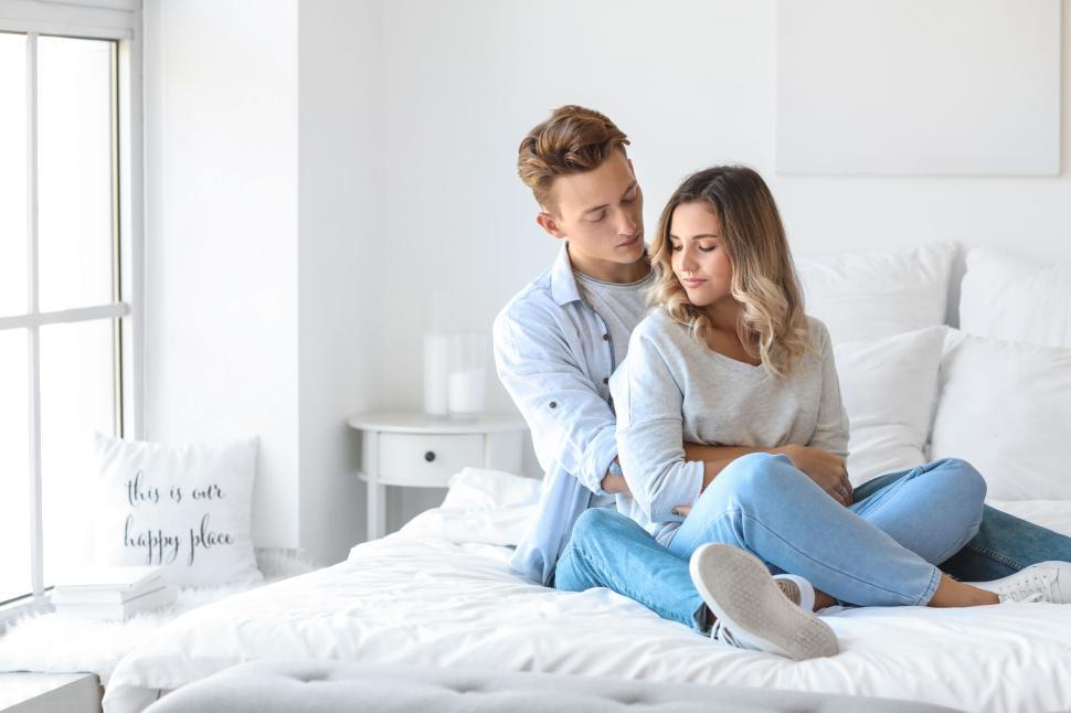 Free Image of Couple sharing an intimate moment on a bed in a bright bedroom 
