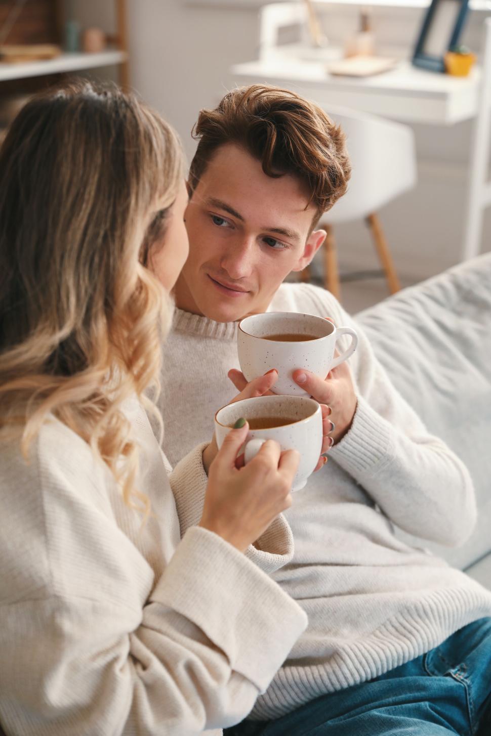 Free Image of Couple sharing coffee on couch enjoying a relaxed conversation 