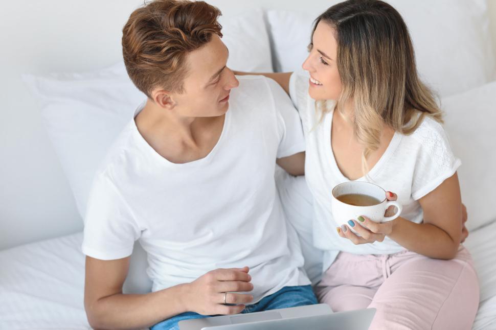 Free Image of Couple drinking coffee together while using laptop, casual setting 