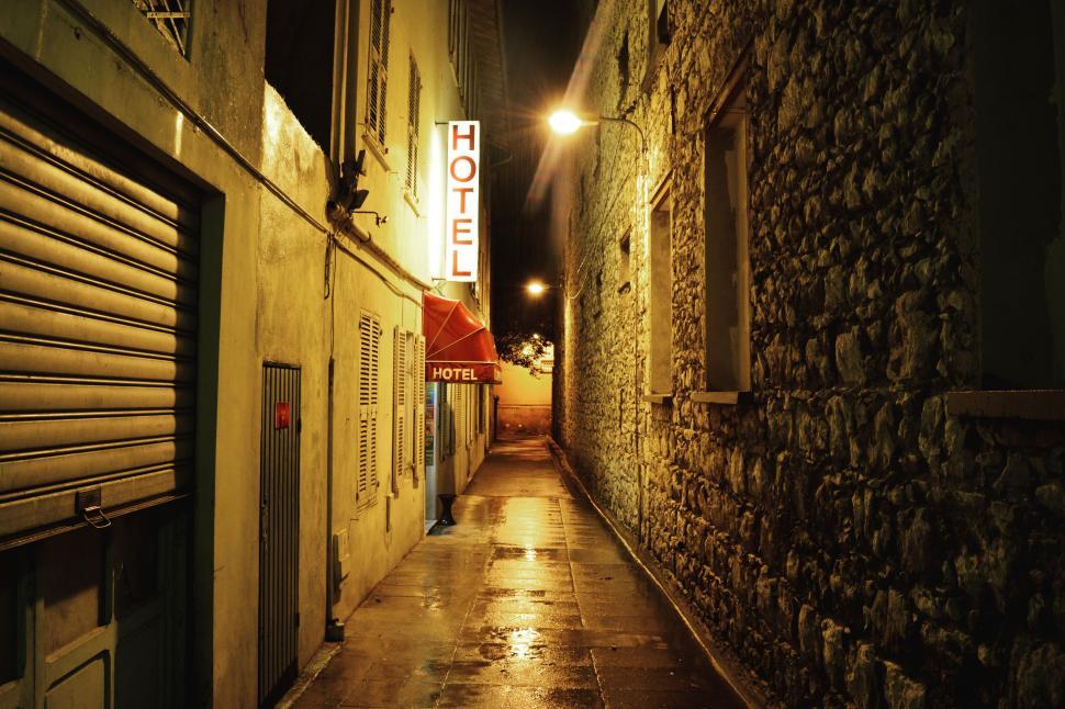 Free Image of Empty alley with hotel sign in a night setting with wet floor 