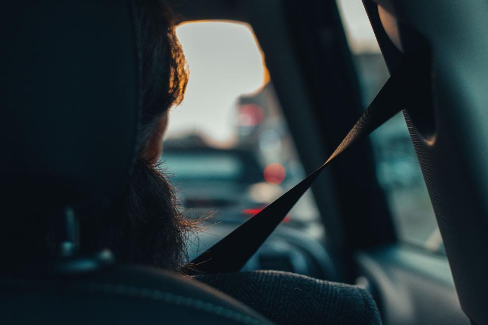 Free Image of Person sits inside car, seatbelt fastened while looking outside. 