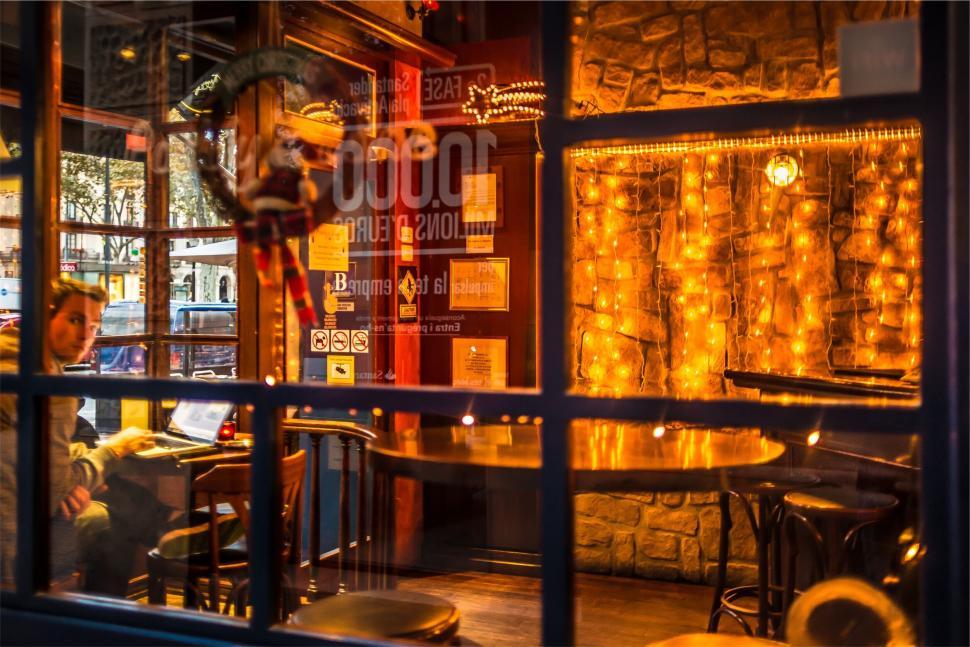 Free Image of A cozy and warmly lit coffee shop interior with wooden furniture. 