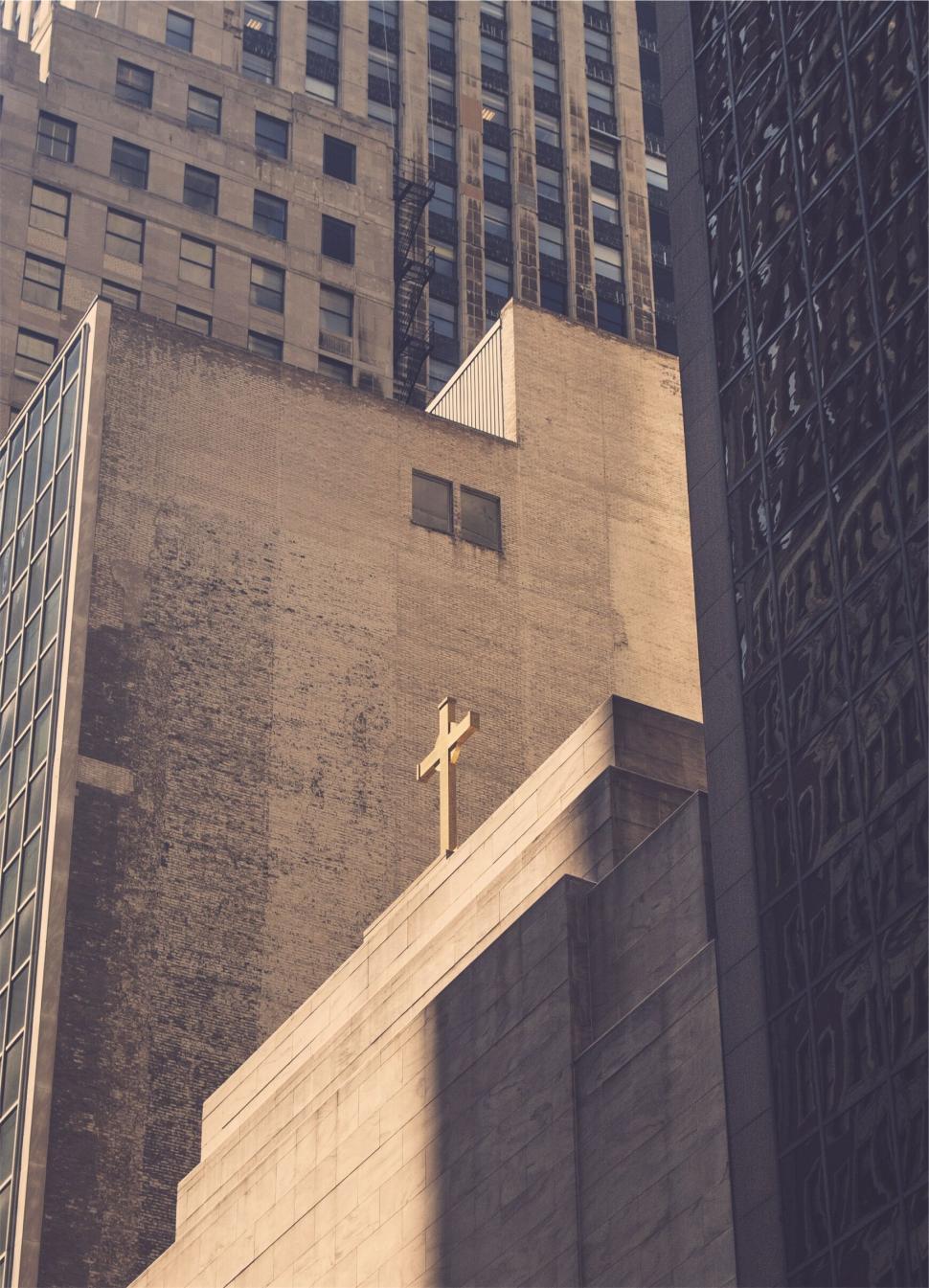 Free Image of Urban skyline with a church cross on a building, warm light. 