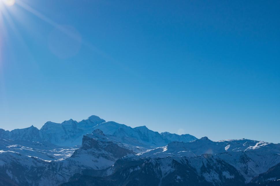 Free Image of Sunny snow-capped mountains scene under bright clear blue sky 