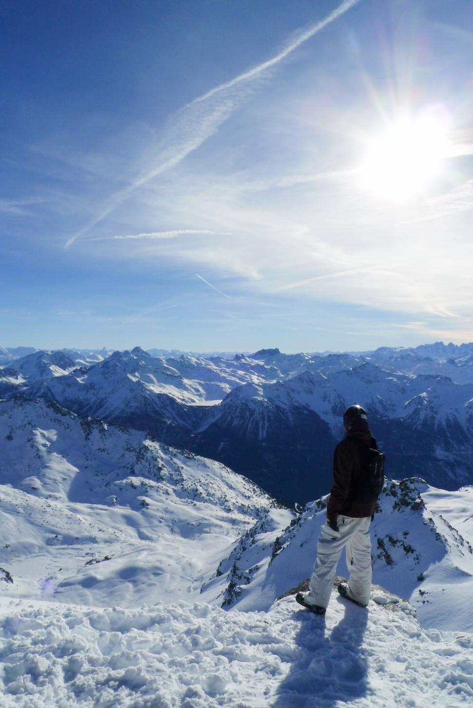 Free Image of Person stands on snowy mountain peak admiring majestic landscape view. 