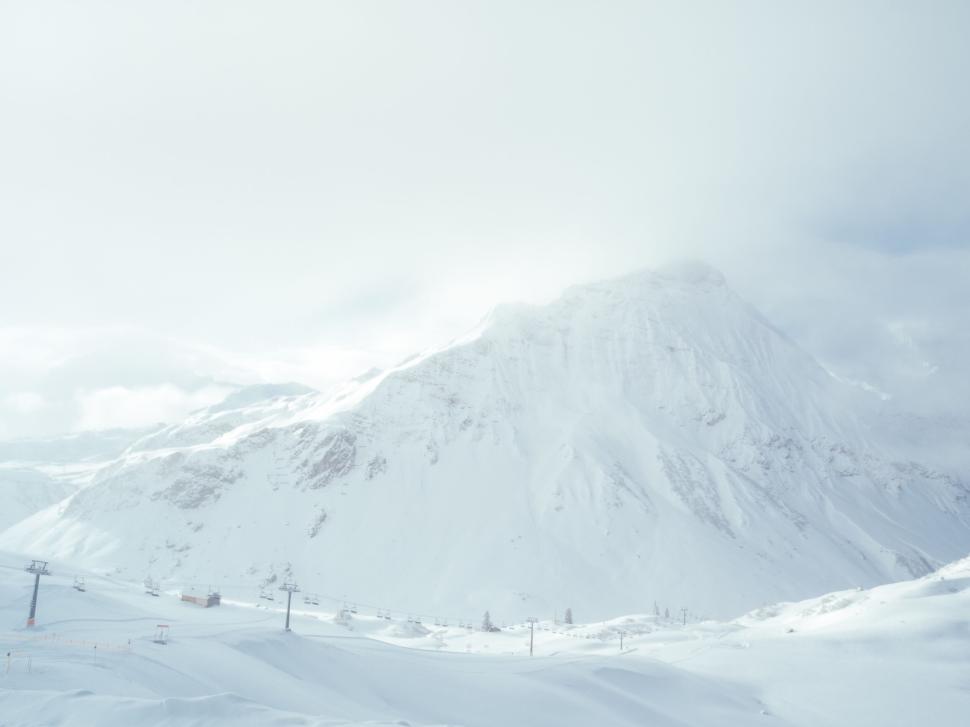 Free Image of Snow-covered mountain under soft sunlight in a serene winter scene. 