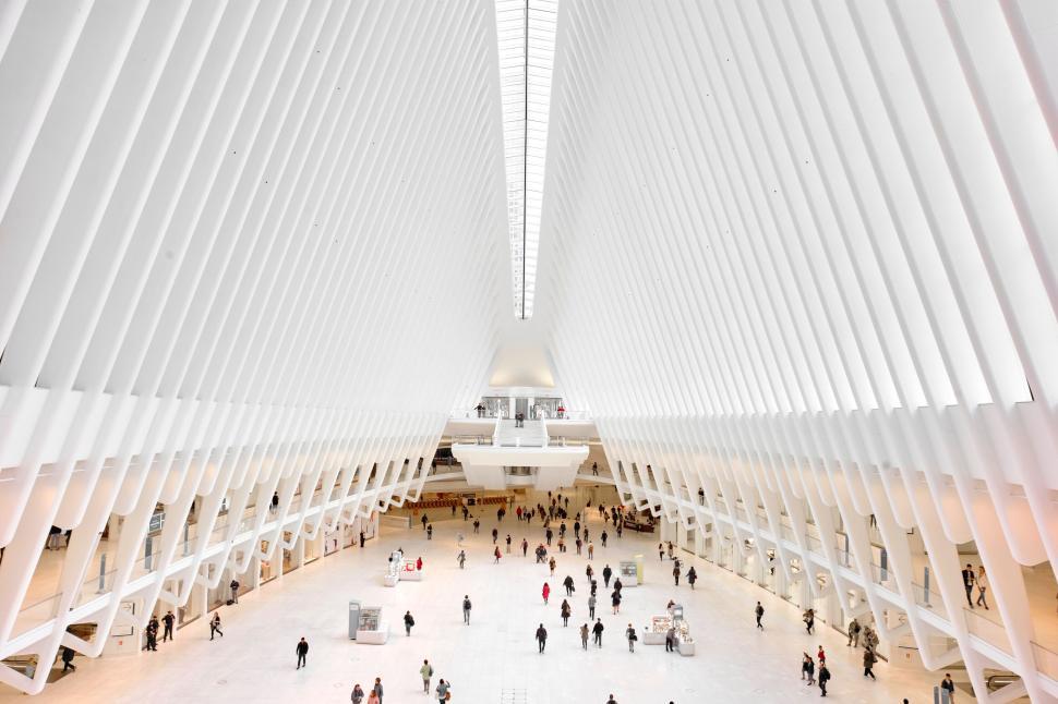 Free Image of Large white architectural space with people walking inside and bright light 