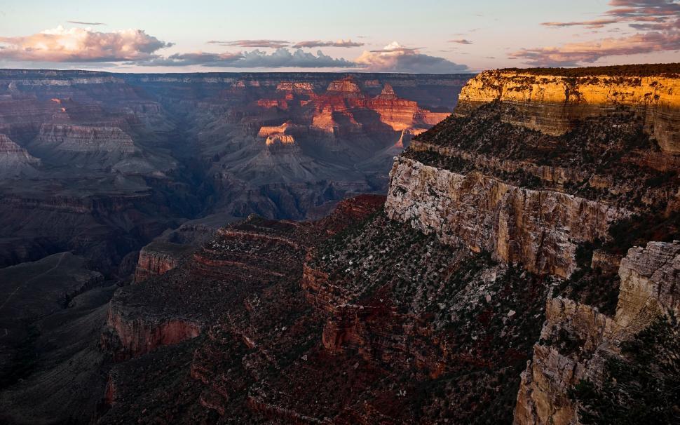 Free Image of Sunset view of a vast canyon with layered rock formations and shadows 