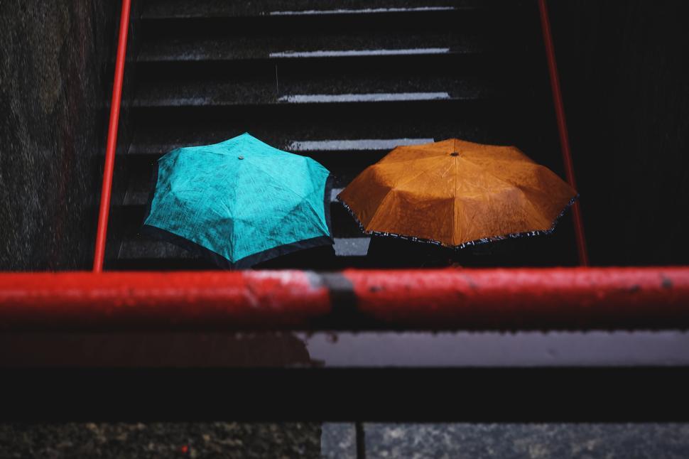 Free Image of Two vibrant umbrellas resting on wet steps during a rainy day. 