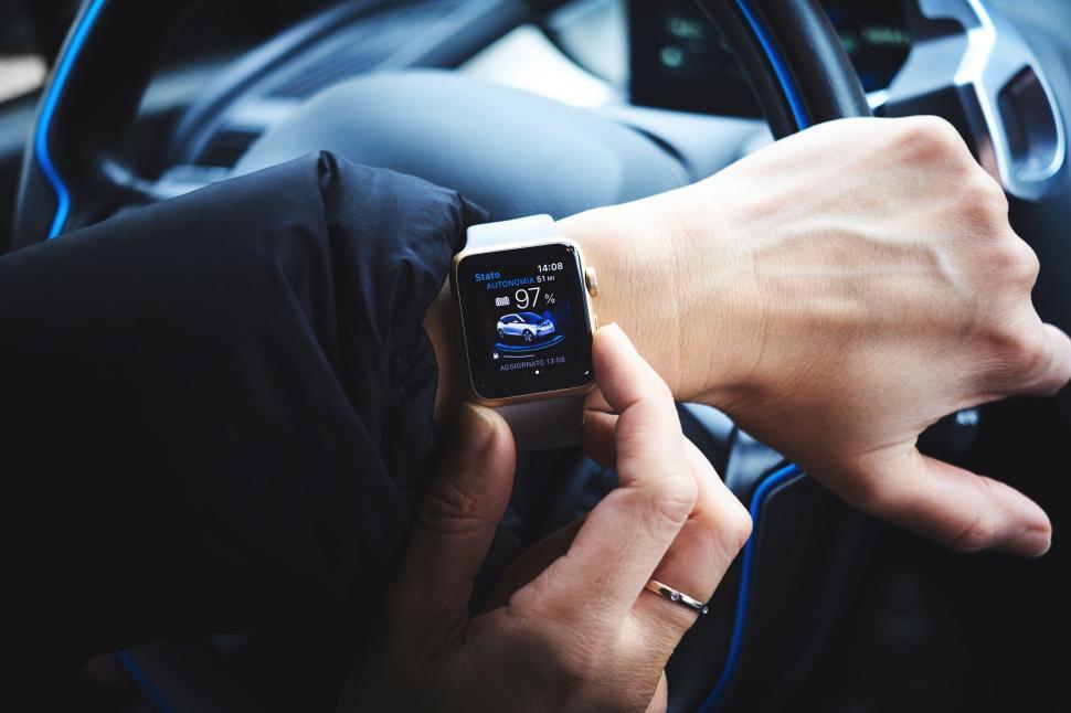 Free Image of Smartwatch on wrist displaying car app interface, hand on steering 