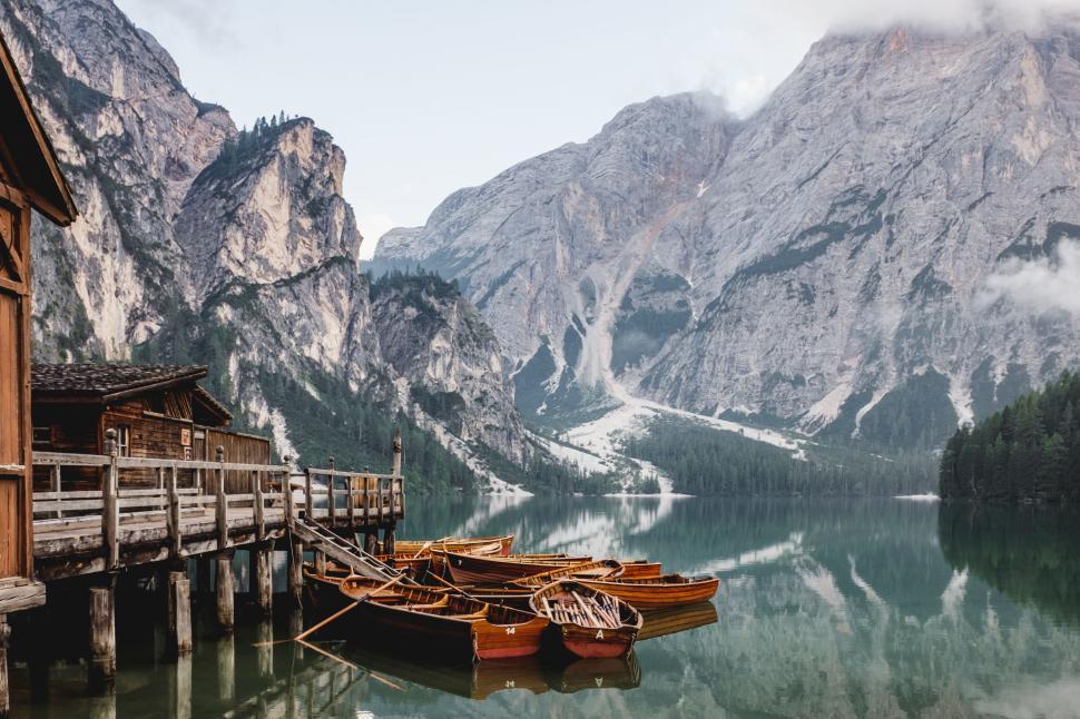 Free Image of Wooden boats docked at a serene lake with mountain reflections 