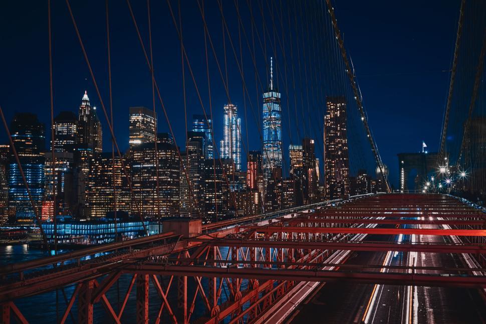 Free Image of Illuminated city skyline at night viewed from a bridge with lights 