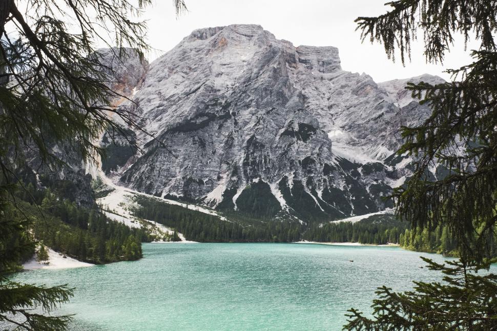 Free Image of Majestic mountain view with a turquoise lake foregrounded by trees 