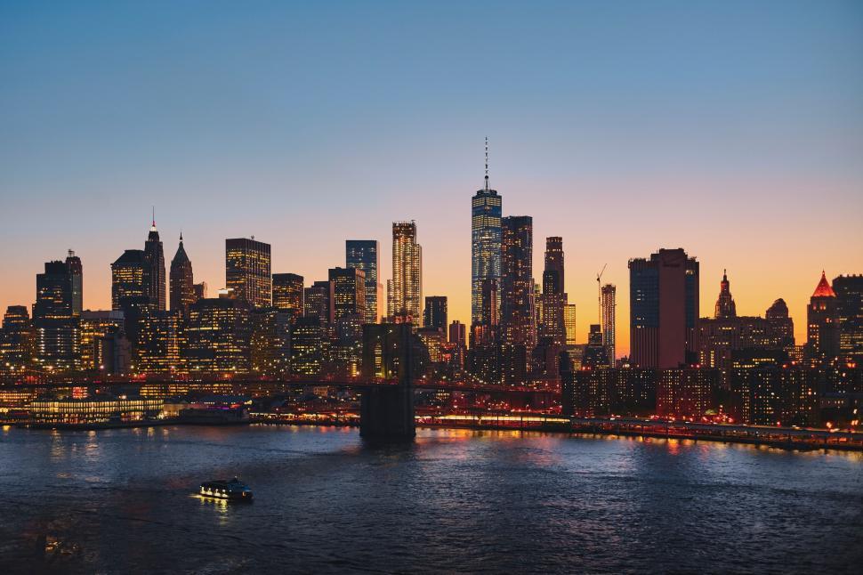 Free Image of City skyline during sunset with reflections on the water surface 