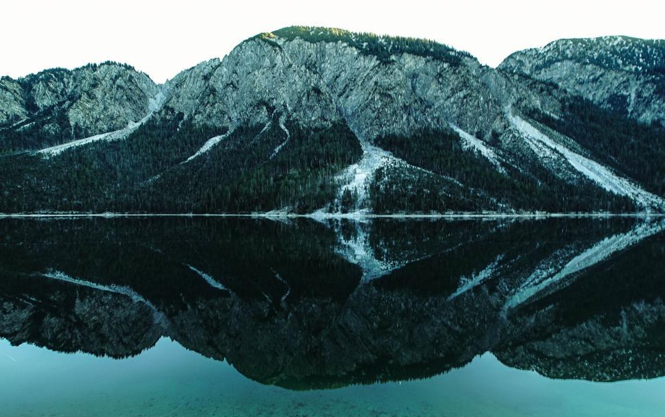 Free Image of Symmetrical reflection of mountain ridge on calm lake surface 