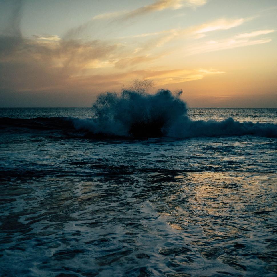 Free Image of Waves crashing in the ocean during sunset with vibrant colors. 