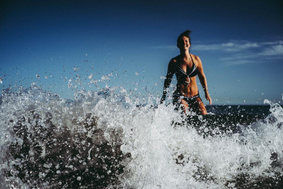 Free Image of Person wearing swimming trunk emerged in ocean waves against clear sky. 