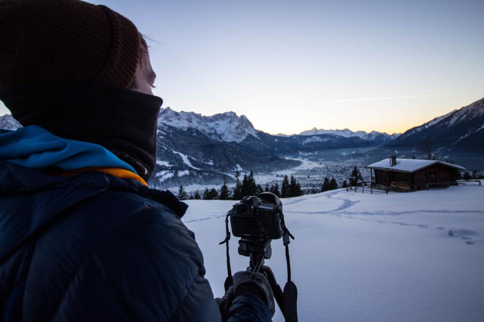 Free Image of Photographer capturing snow-covered mountains at dawn 