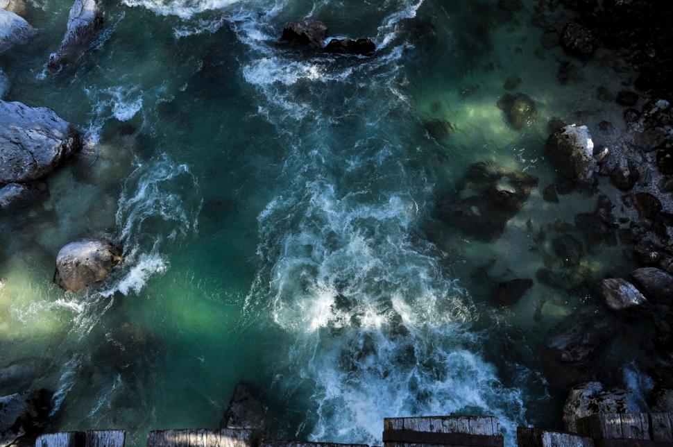 Free Image of Rushing river with rocks viewed from above, vibrant teal waters 