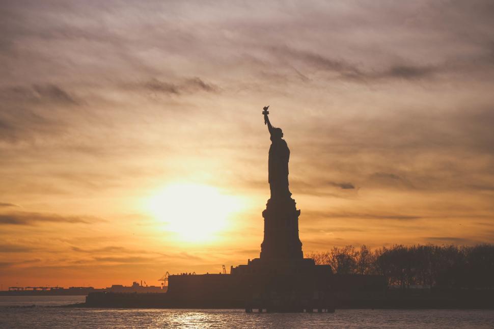 Free Image of Sunset silhouette of the Statue of Liberty against colorful sky 