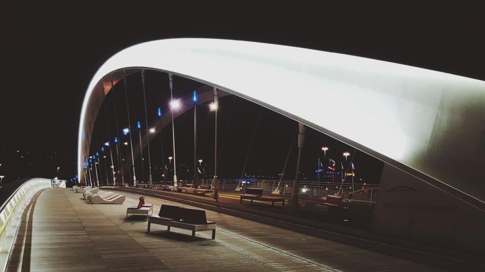 Free Image of Modern, illuminated pedestrian bridge against a dark night sky. 