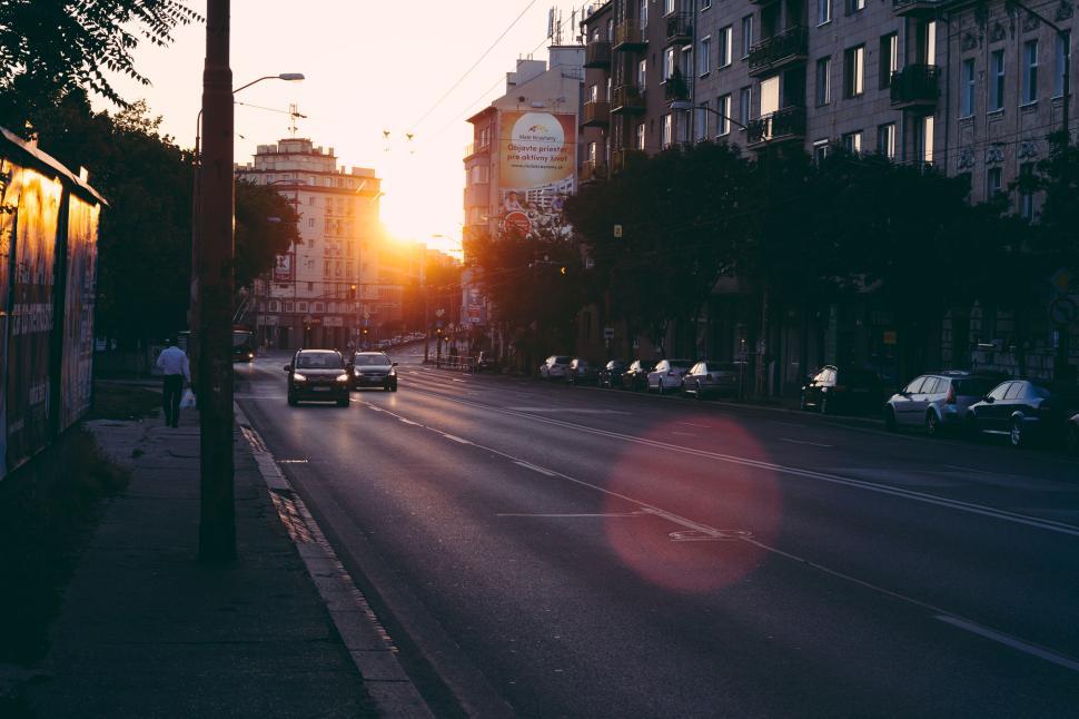 Free Image of City street at sunrise with cars, buildings, and early morning light 