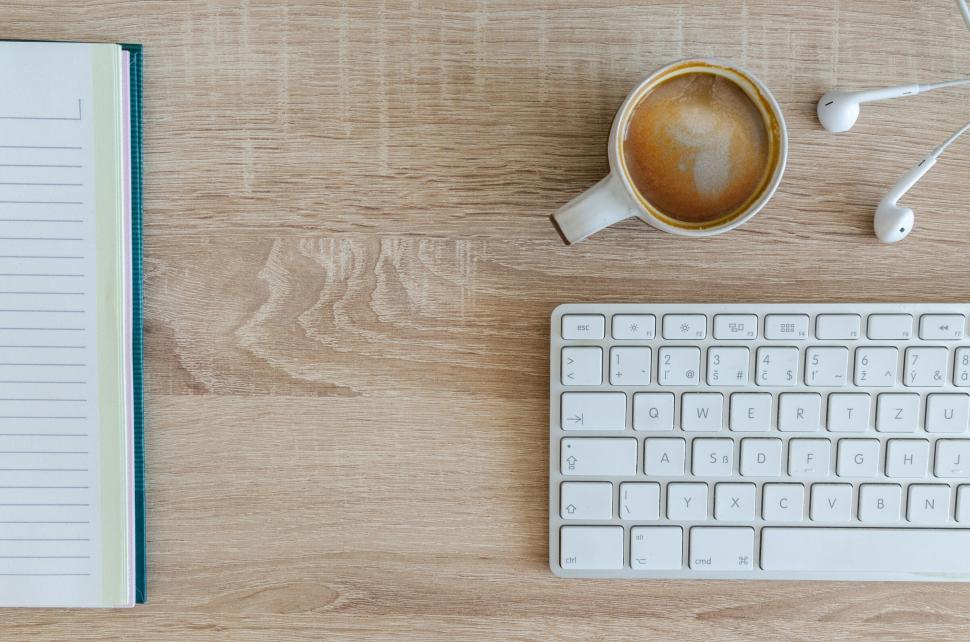 Free Image of A top-down view of a workspace with a coffee cup and a keyboard 