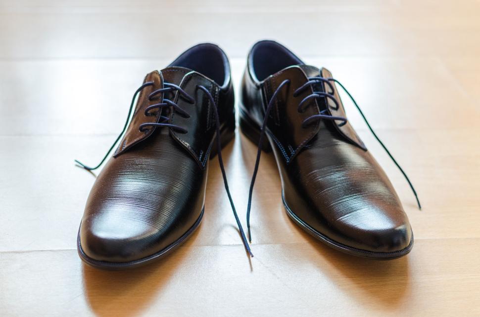 Free Image of Pair of polished black formal shoes on a wooden floor surface. 