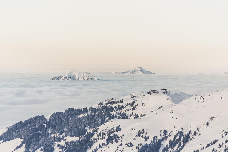 Free Image of Snow-capped mountains with a sea of clouds below and distant peaks 